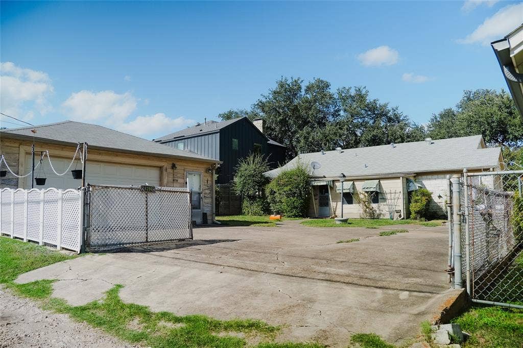 Detached garage featuring a concrete driveway, metal privacy fencing, and exterior lighting