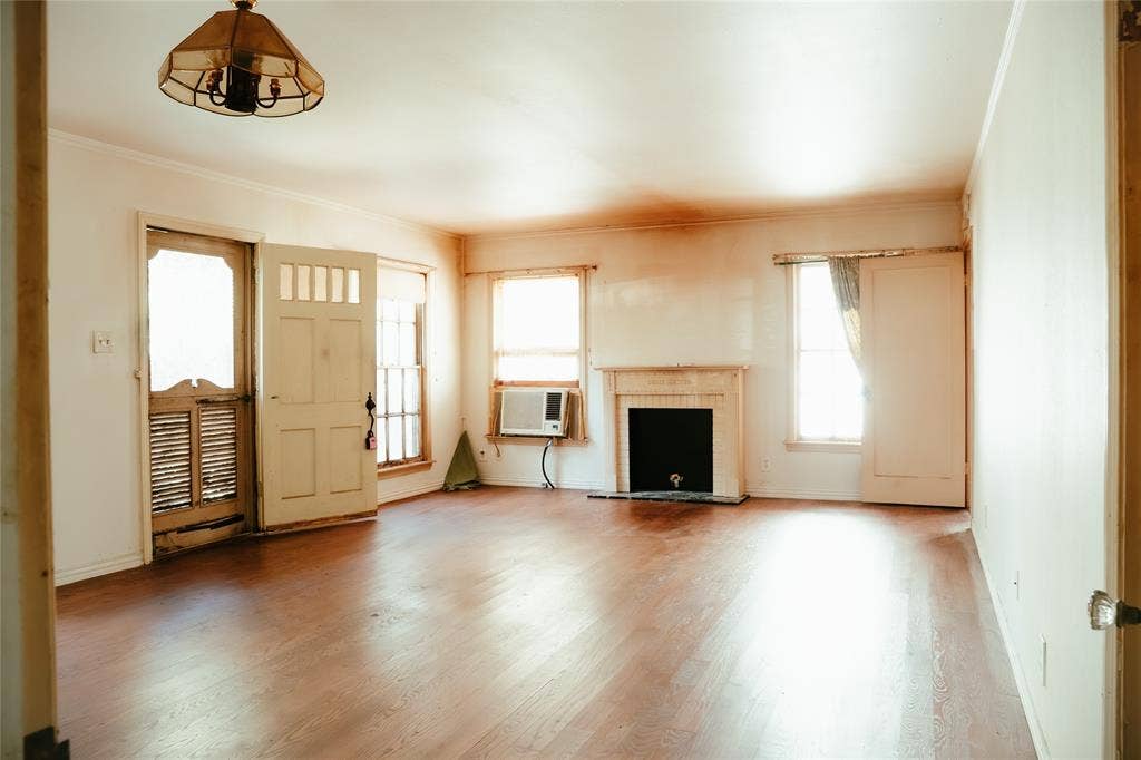 Living area featuring wood-finish flooring, a fireplace with a decorative mantel, multipane windows, a multi-lite exterior door, and a multi-arm hanging light fixture