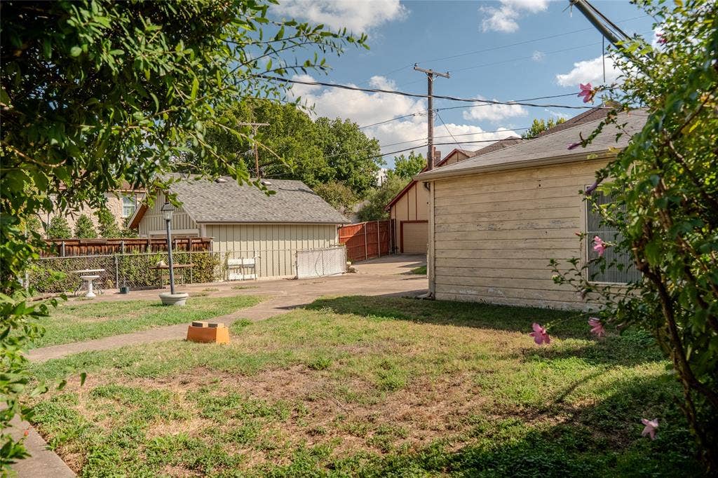 Exterior space featuring a concrete driveway, detached garage with horizontal siding, and perimeter wood fencing