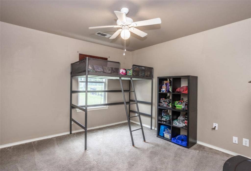 Neutral-toned interior featuring carpeting, a single-light ceiling fan, and a window with a built-in sill