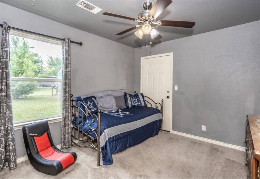 Interior room featuring neutral grey wall paint, carpeted flooring, a multi-blade ceiling fan with integrated lighting, and a single-pane window