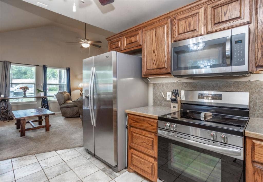 Kitchen featuring wood cabinetry, stainless steel refrigerator, over-the-range microwave, and electric range