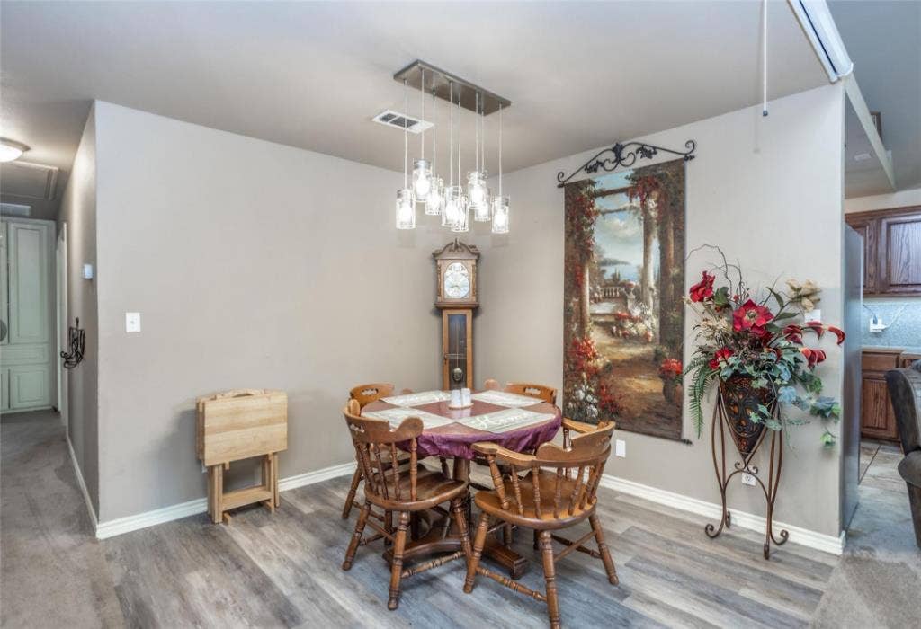 Multi-pendant light fixture with glass shades, wood-finish flooring, and neutral wall tones