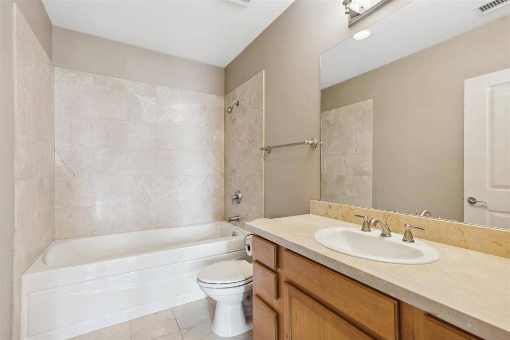 500 Throckmorton Street, #2702, Fort Worth, TX 76102 Bathroom featuring a vanity with an integrated basin, tile-surround bathtub, large wall-mounted mirror, and metal fixtures