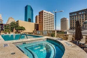 500 Throckmorton Street, #2702, Fort Worth, TX 76102 Rooftop swimming pool and spa featuring stone decking, tile accents, and an urban skyline backdrop