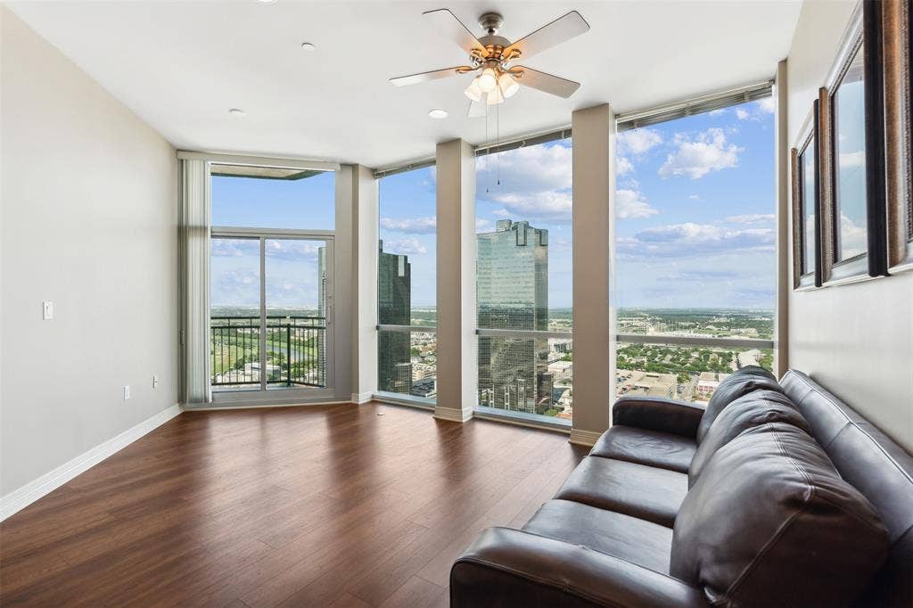 500 Throckmorton Street, #2702, Fort Worth, TX 76102 Floor-to-ceiling windows, wood-finish flooring, sliding glass door with access to a balcony, and a ceiling fan with integrated light fixture