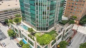 500 Throckmorton Street, #2702, Fort Worth, TX 76102 High-rise tower featuring a glass facade, expansive terrace with an outdoor swimming pool, integrated green space, and manicured landscaping