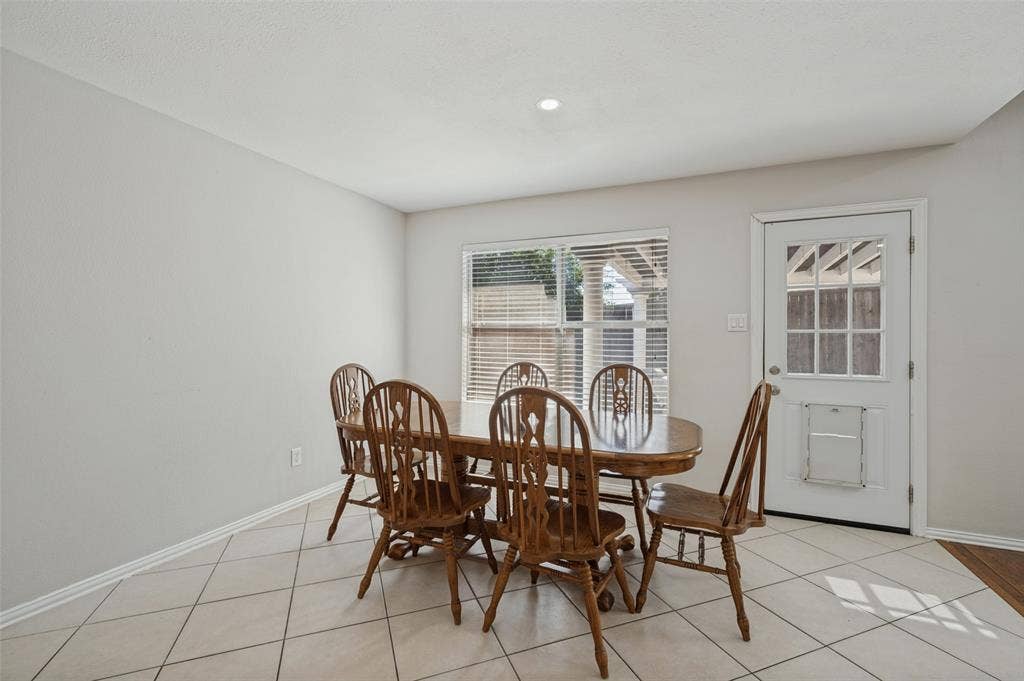 Dining space featuring neutral wall tones, large-format diagonal tile flooring, a recessed ceiling light, and a single-light exterior door with glass pane detailing