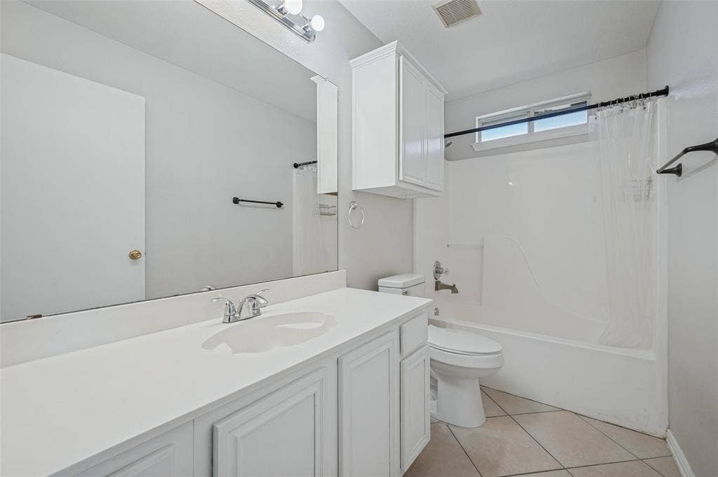 Bathroom featuring white cabinetry, an integrated sink with chrome fixtures, a large wall-mounted mirror, a tub-shower combination with surround, and tile flooring