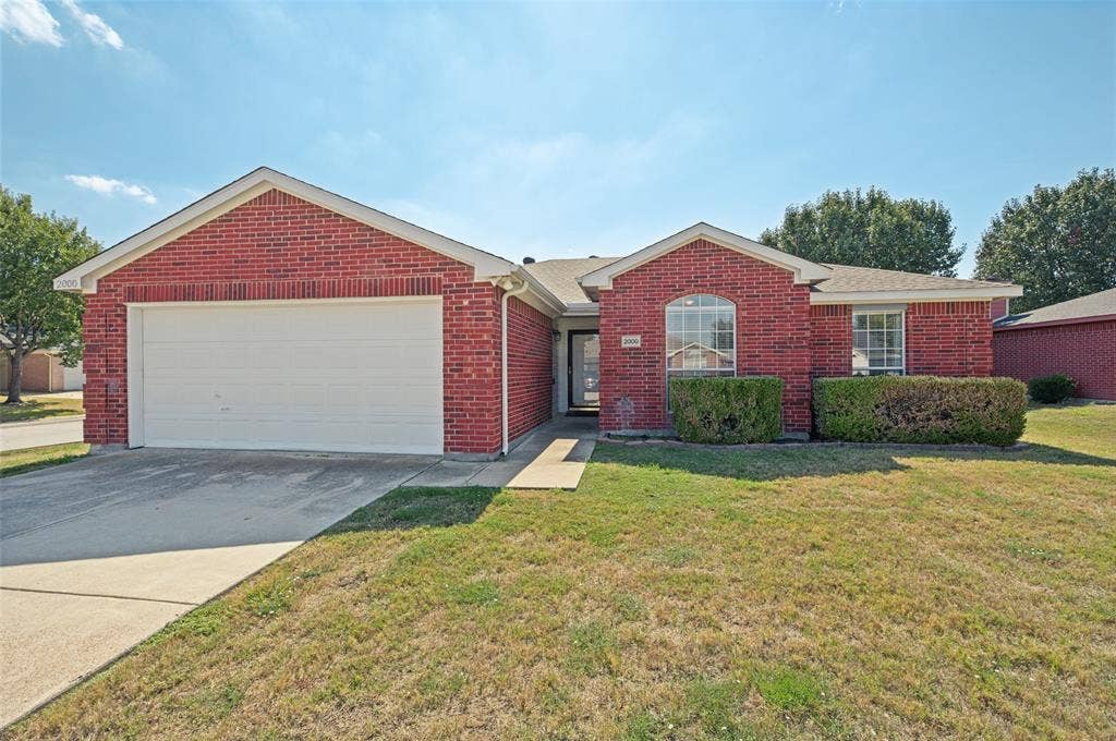 Red brick exterior featuring a front-facing attached garage, arched window detail, concrete driveway, and covered entryway