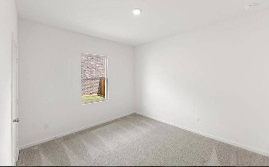 Neutral interior space featuring carpeted flooring, recessed lighting, and a single-pane window