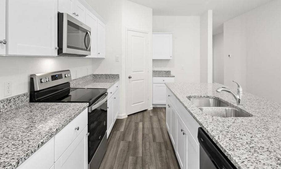 Kitchen featuring white cabinetry, stone-finish countertops, stainless steel appliances, a double-basin undermount sink, and wood-finish flooring