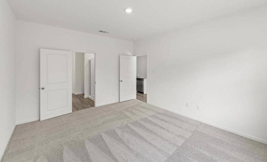 Neutral-toned wall-to-wall carpeting, recessed ceiling lighting, and two-panel interior doors