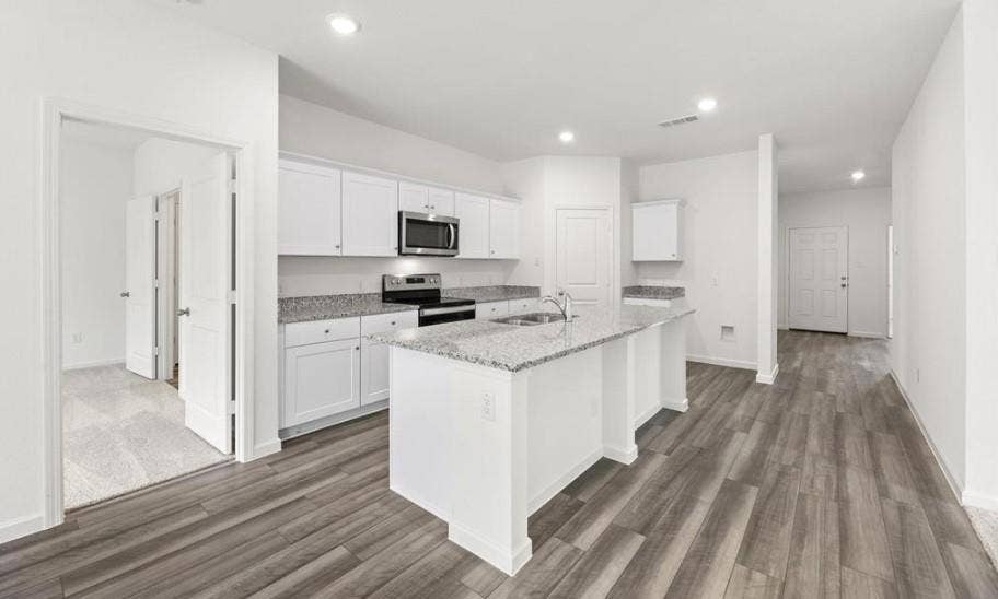 Kitchen featuring white cabinetry, stone-surface countertops, center island, recessed lighting, and wood-finish flooring