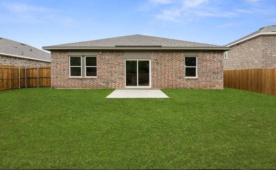 Brick exterior, rear concrete patio, sliding glass doors, and fully enclosed wood fencing