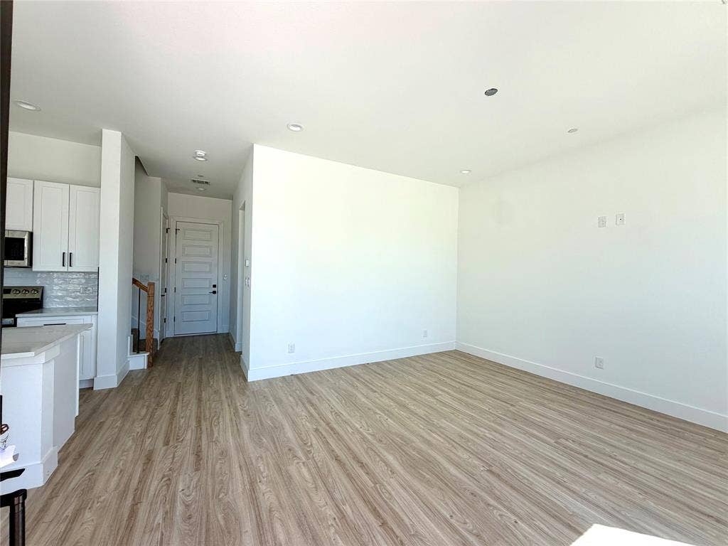 8902 Lowell Street, Rowlett, TX 75089 Open-concept interior featuring wood-finish flooring, recessed lighting, white cabinetry, and a neutral color palette
