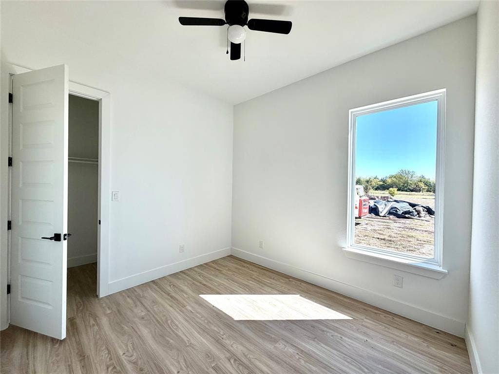 8902 Lowell Street, Rowlett, TX 75089 Interior space featuring wood-finish flooring, a five-panel interior door, a ceiling fan with integrated lighting, and a window with a exterior landscape outlook