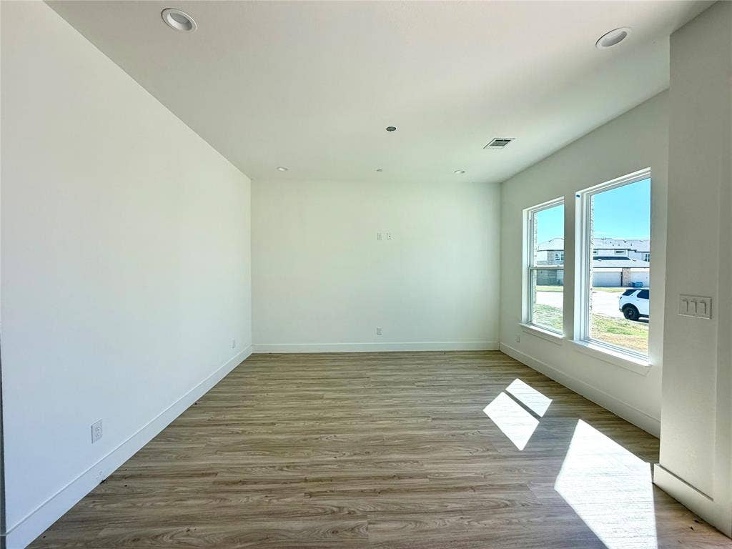 8902 Lowell Street, Rowlett, TX 75089 Open-concept room featuring neutral wall tones, wood-finish flooring, dual windows with exterior exposure, and recessed lighting