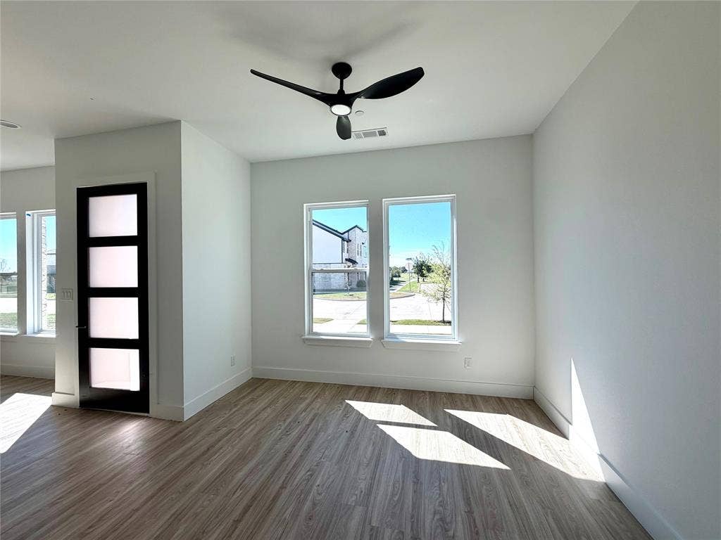 8902 Lowell Street, Rowlett, TX 75089 Wood-finish flooring, matte black three-blade ceiling fan with integrated lighting, and a modern single-panel door featuring four frosted glass inserts
