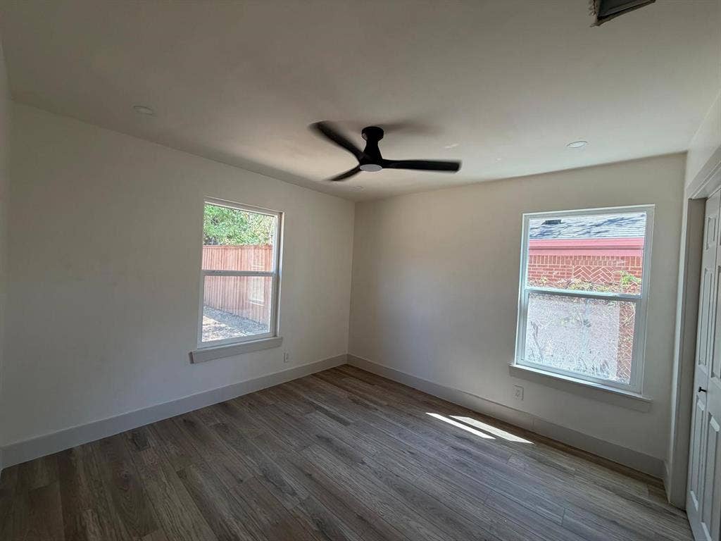 Interior space featuring wood-finish flooring, dual windows with natural light, recessed lighting, and a matte black ceiling fan