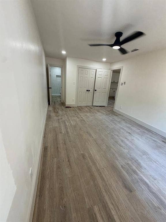 Wood-finish flooring, matte black ceiling fan, recessed lighting, and double-panel closet doors