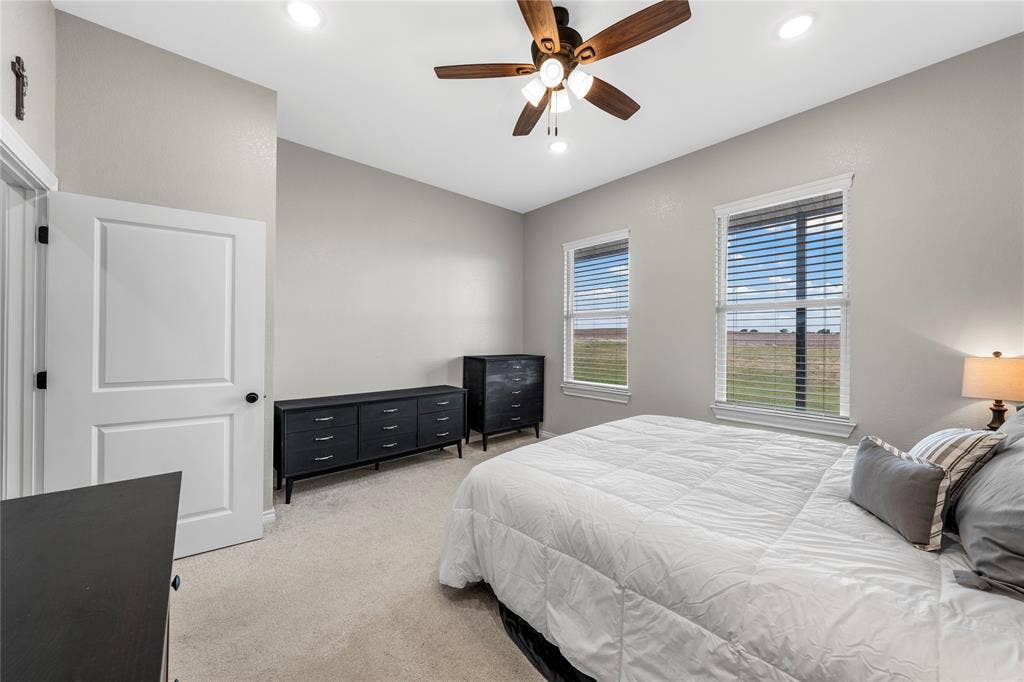 Room featuring neutral wall paint, carpeted flooring, recessed lighting, a ceiling fan with integrated lighting, and two windows with horizontal blinds