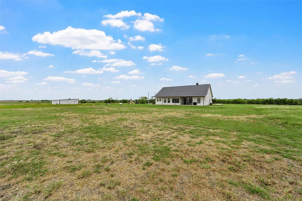 Expansive lot featuring a single-story residence with a metal roof and a detached outbuilding