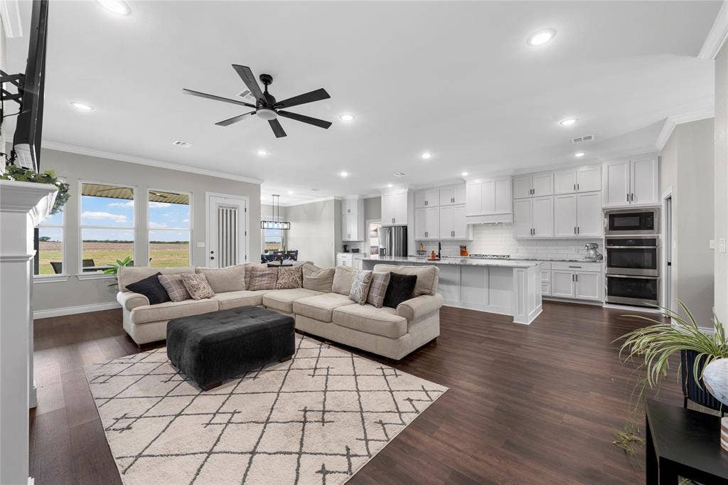 Open-concept living space featuring wood-finish flooring, white cabinetry, a large kitchen island, recessed lighting, and a ceiling fan