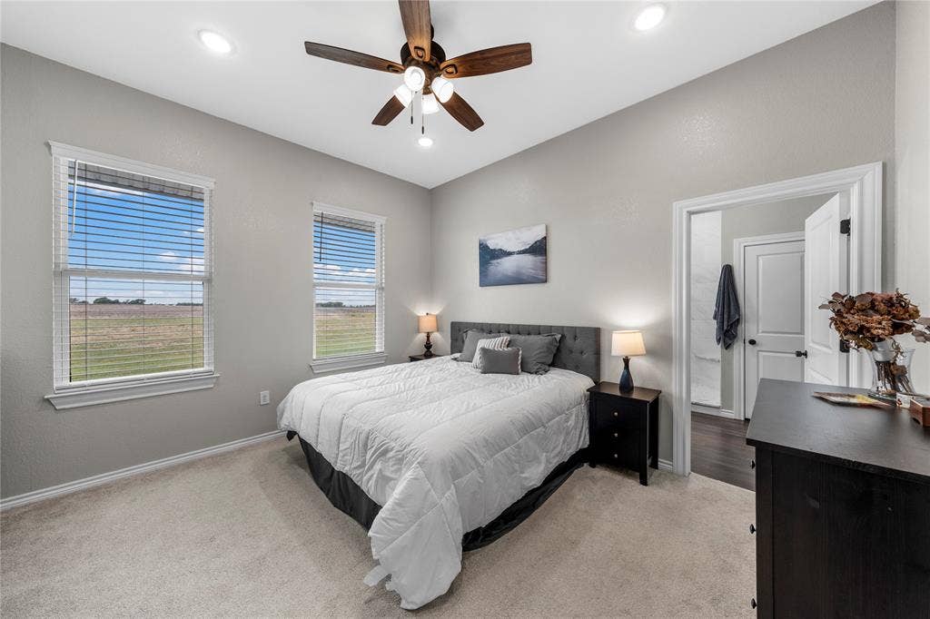 Neutral-toned interior featuring high ceilings, recessed lighting, a multi-blade ceiling fan, and large windows providing natural light