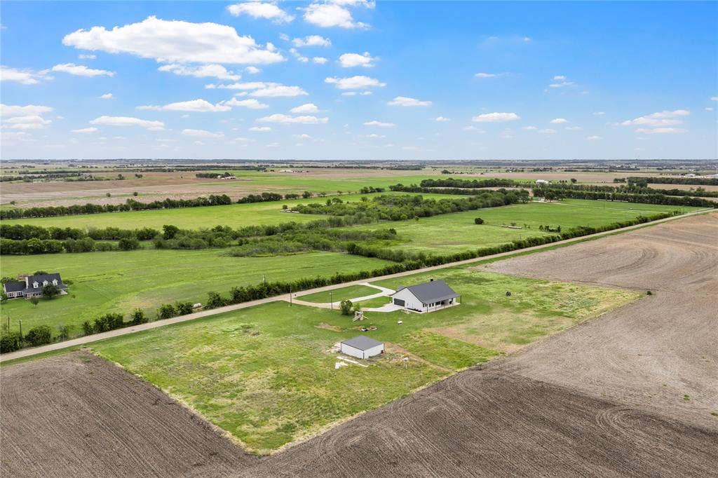 Expansive acreage featuring a single-story residence, a detached structure, concrete driveway, and open pasture land
