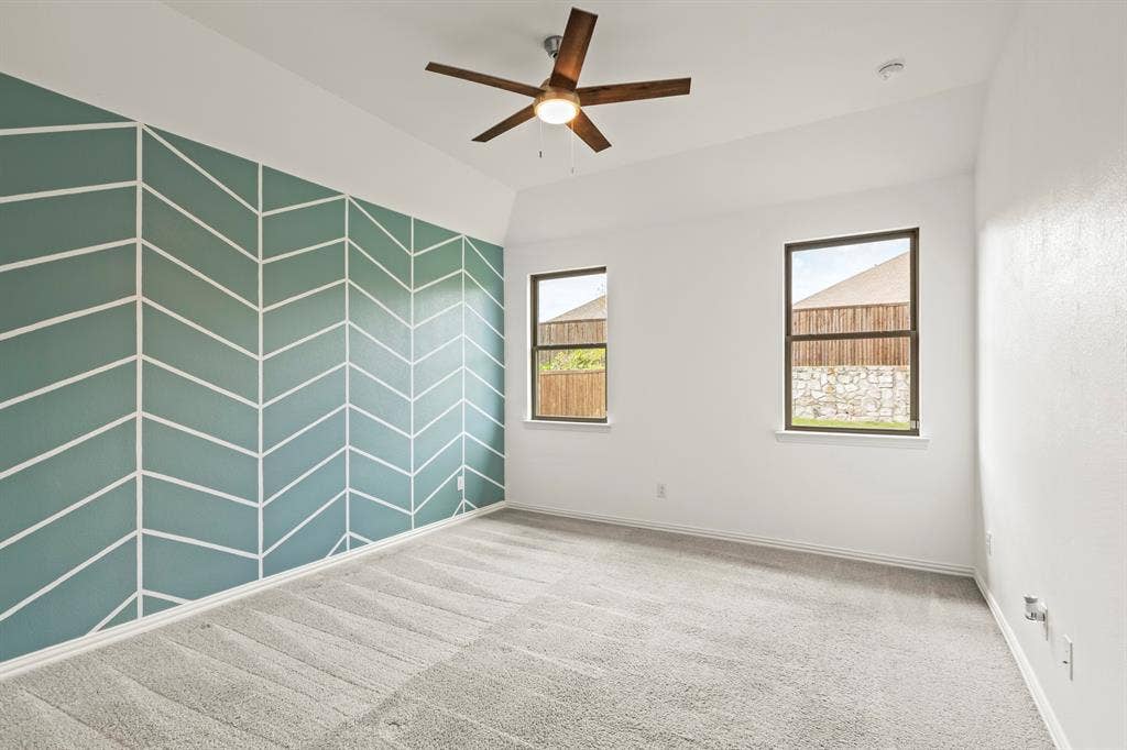 2305 Switchgrass Street, Melissa, TX 75454 Room featuring tray ceilings, neutral carpeting, a dual-tone geometric accent wall, and a central ceiling fan with integrated lighting