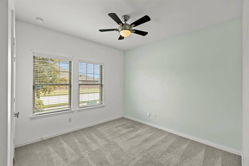 2305 Switchgrass Street, Melissa, TX 75454 Neutral-toned carpeted flooring, two double-pane windows with horizontal blinds, and a central ceiling fan with integrated lighting