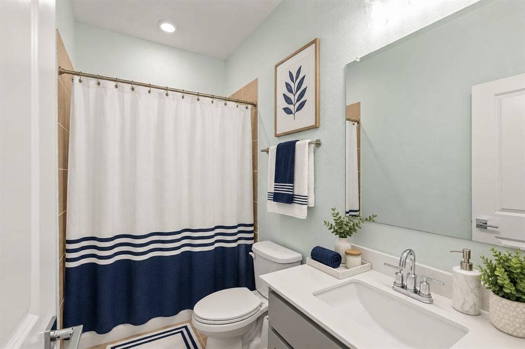 2305 Switchgrass Street, Melissa, TX 75454 Bathroom featuring a vanity with a white countertop and rectangular undermount sink, chrome dual-handle faucet, large wall-mounted mirror, and tile surround in the shower area. Virtual photo