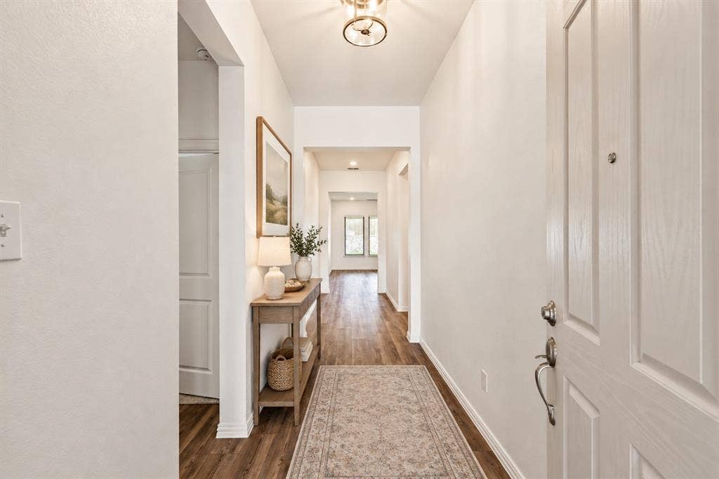 2305 Switchgrass Street, Melissa, TX 75454 Entryway featuring wood-finish flooring, a flush-mount ceiling light fixture, and a paneled entry door with satin nickel hardware. Virtual photo