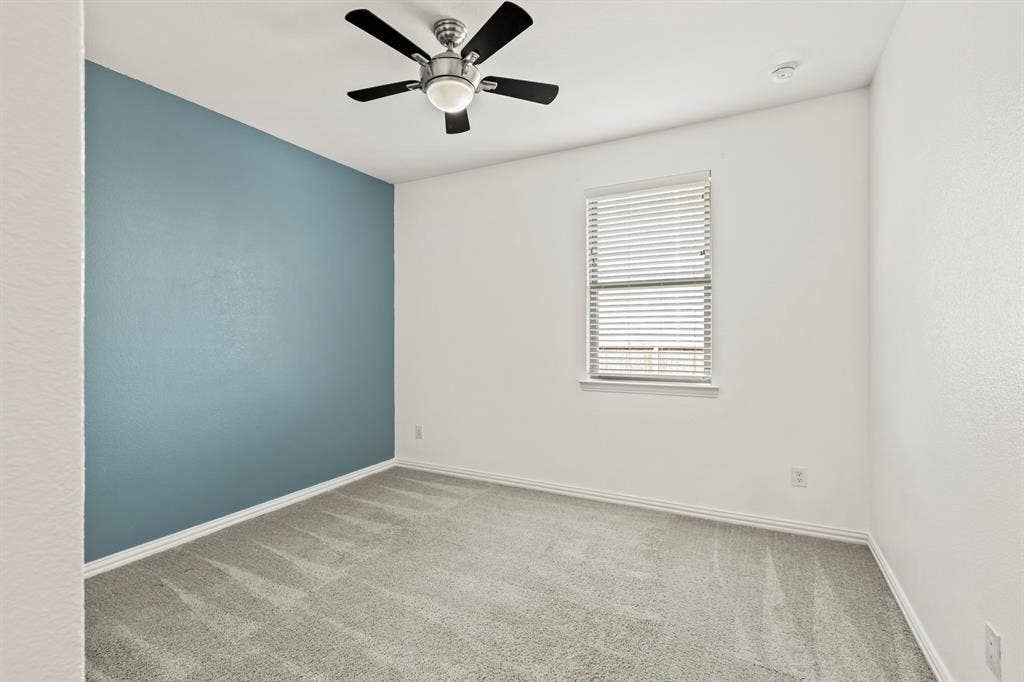 2305 Switchgrass Street, Melissa, TX 75454 Room featuring neutral carpeting, a blue accent wall, a dual-window with horizontal blinds, and a central ceiling fan with integrated lighting