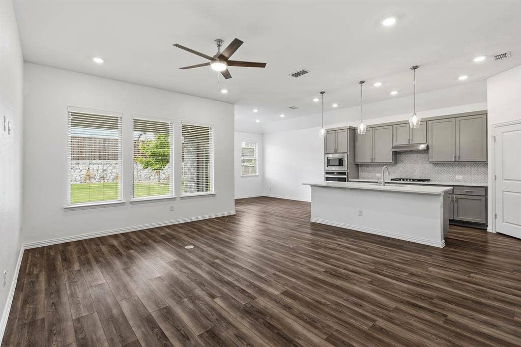 2305 Switchgrass Street, Melissa, TX 75454 Open-concept area featuring wood-finish flooring, a kitchen island with stone countertops, gray cabinetry, recessed lighting, and pendant fixtures