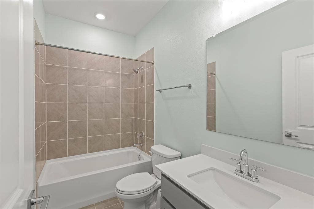 2305 Switchgrass Street, Melissa, TX 75454 Bathroom featuring a white vanity with a composite countertop, an integrated rectangular sink, a shower-tub combination with tiled surround, and a wall-mounted mirror