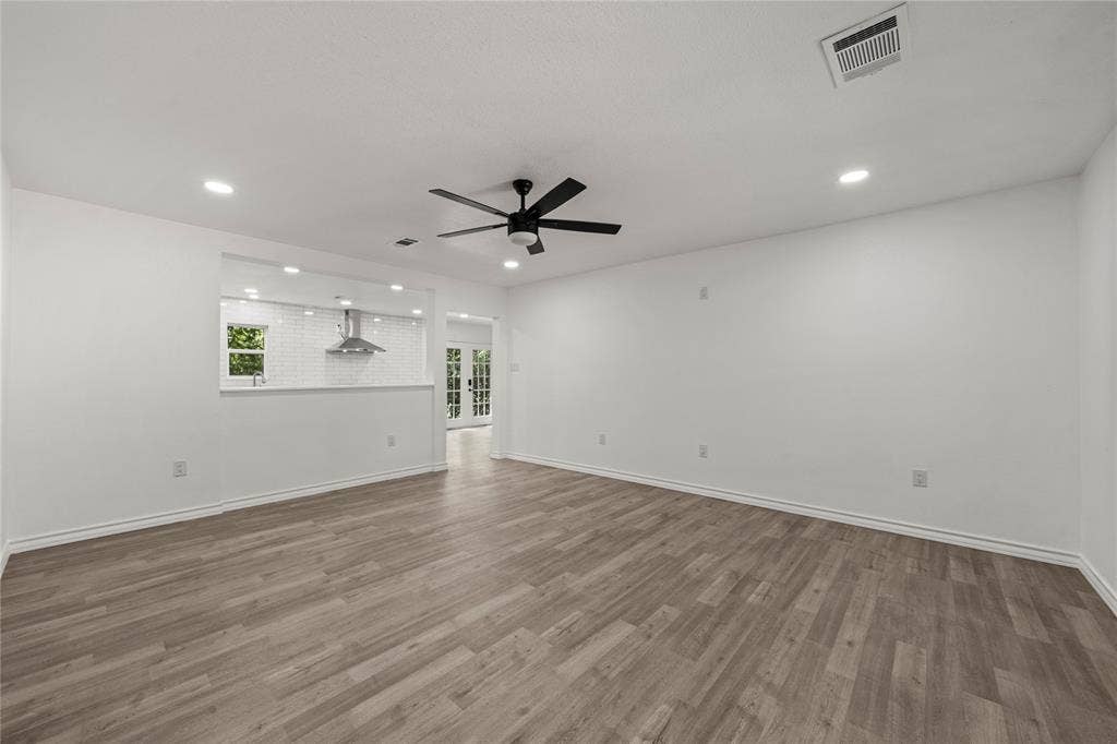 Neutral interior space featuring wood-finish flooring, recessed lighting, and a multi-blade ceiling fan