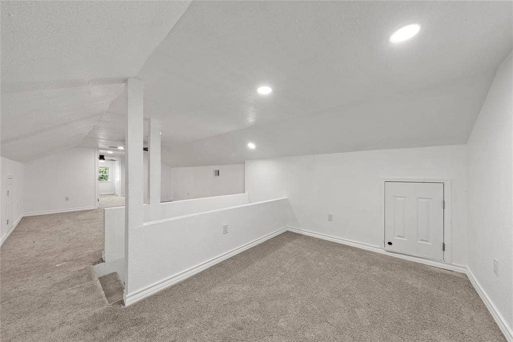 Vaulted ceilings featuring recessed lighting, neutral carpeting, and built-in access doors