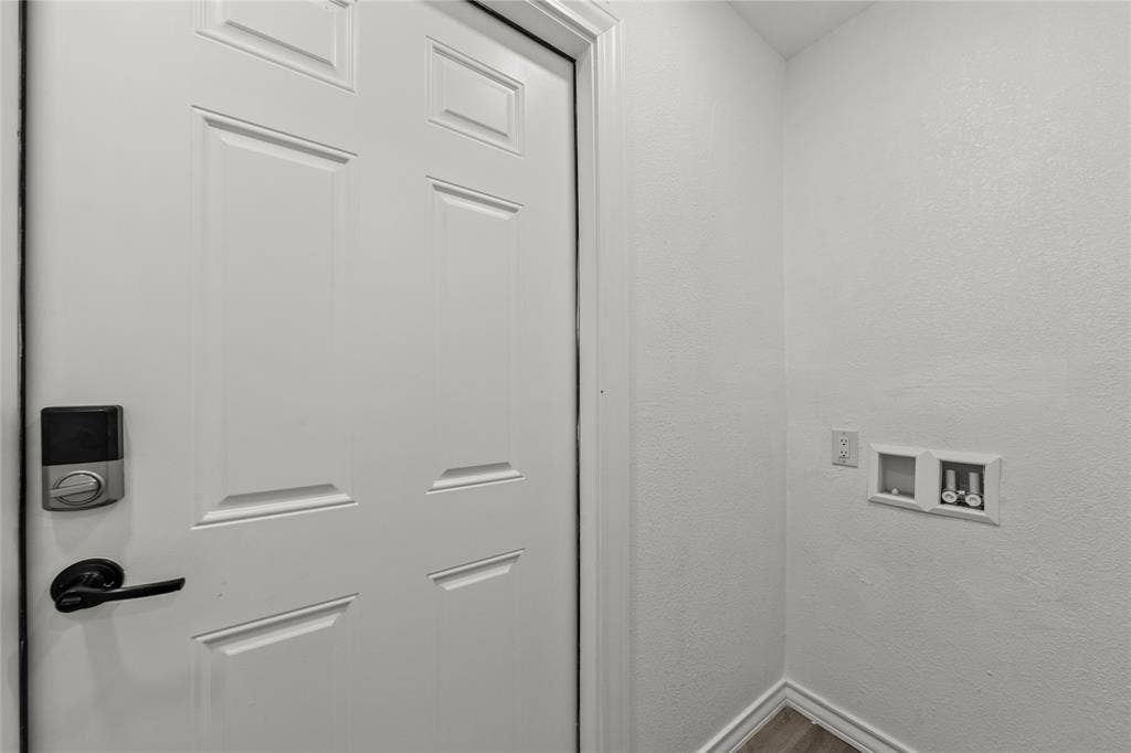 Six-panel door featuring a matte black lever handle and electronic keypad deadbolt, paired with dedicated laundry utility connections