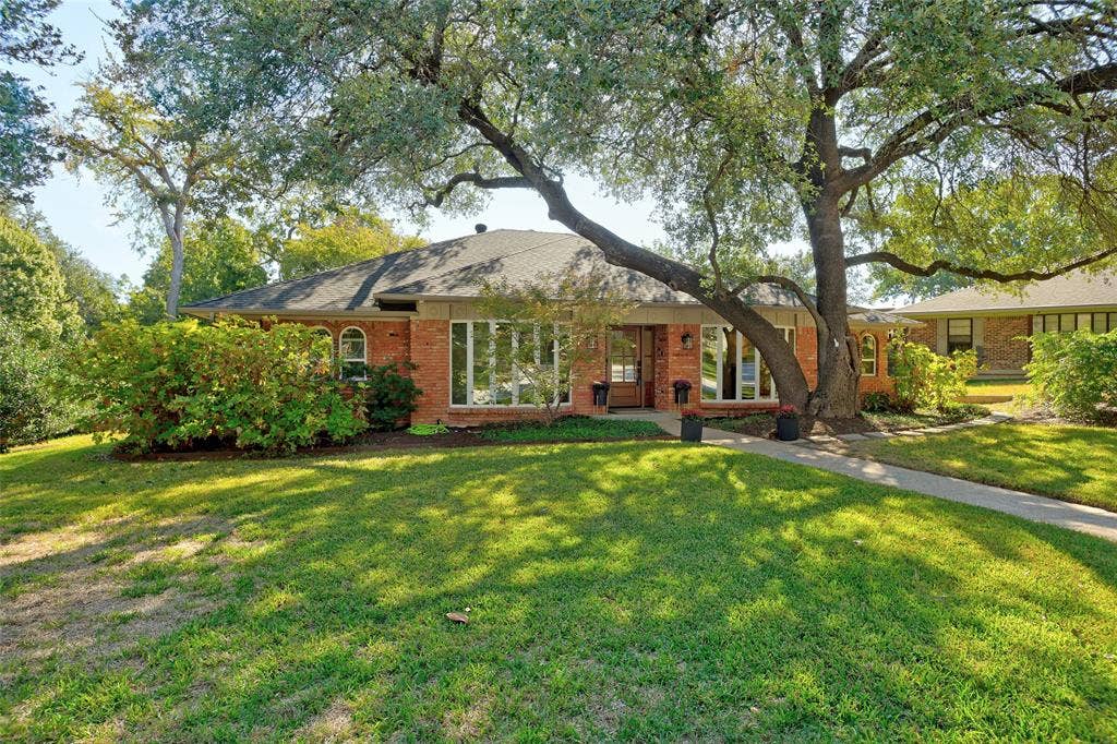 Single-story brick exterior featuring a multi-pane bay window, an arched window detail, and a concrete walkway