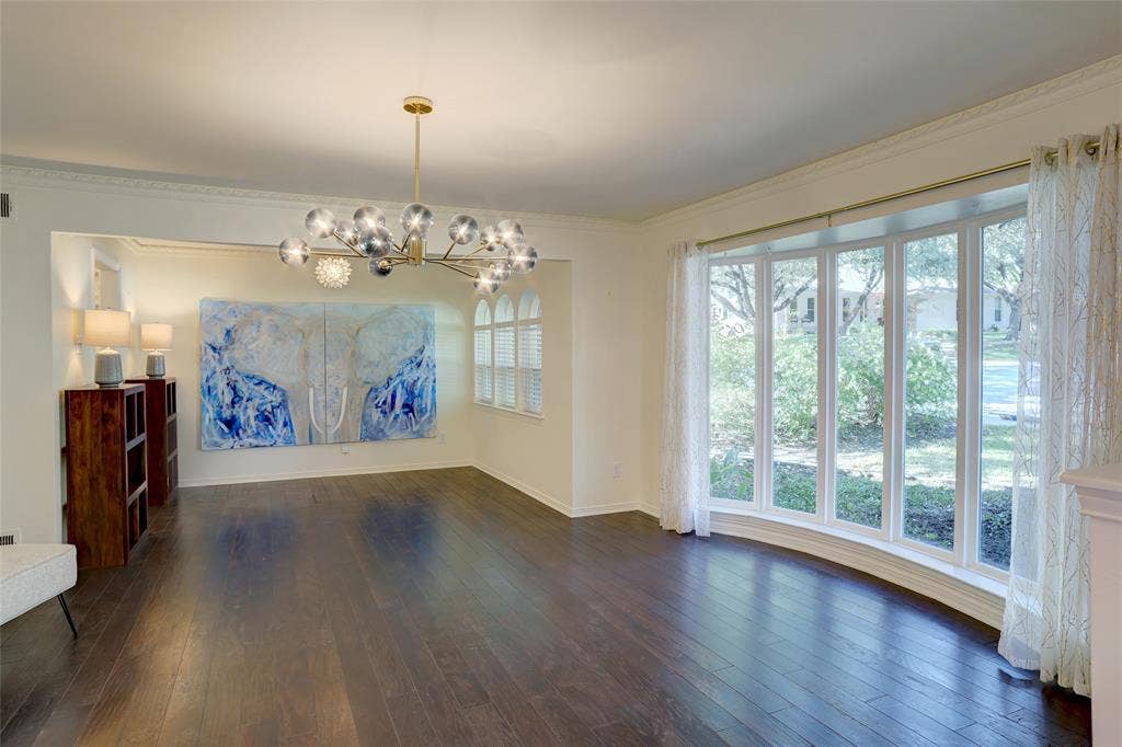 Wood-finish flooring, multi-panel bay window, contemporary multi-light metal chandelier, crown molding, and arched window detailing