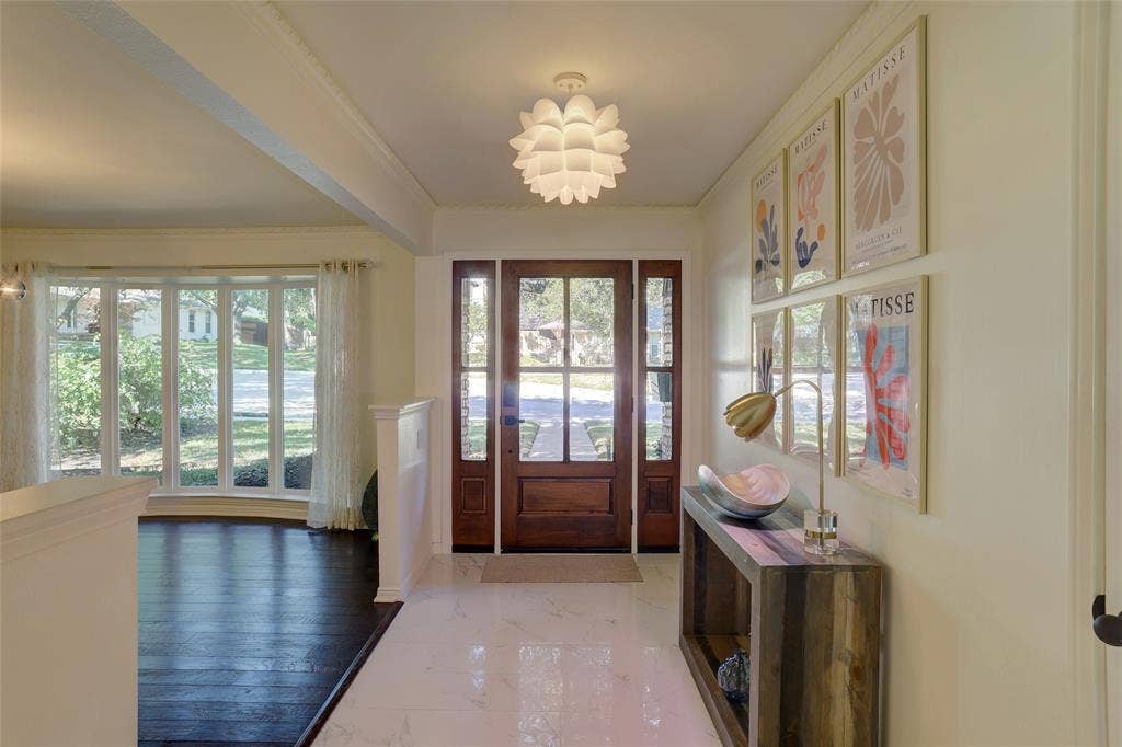 Entryway featuring a wood-framed front door with side panels, polished stone flooring, dark wood-finish flooring, and a decorative petal-style ceiling fixture