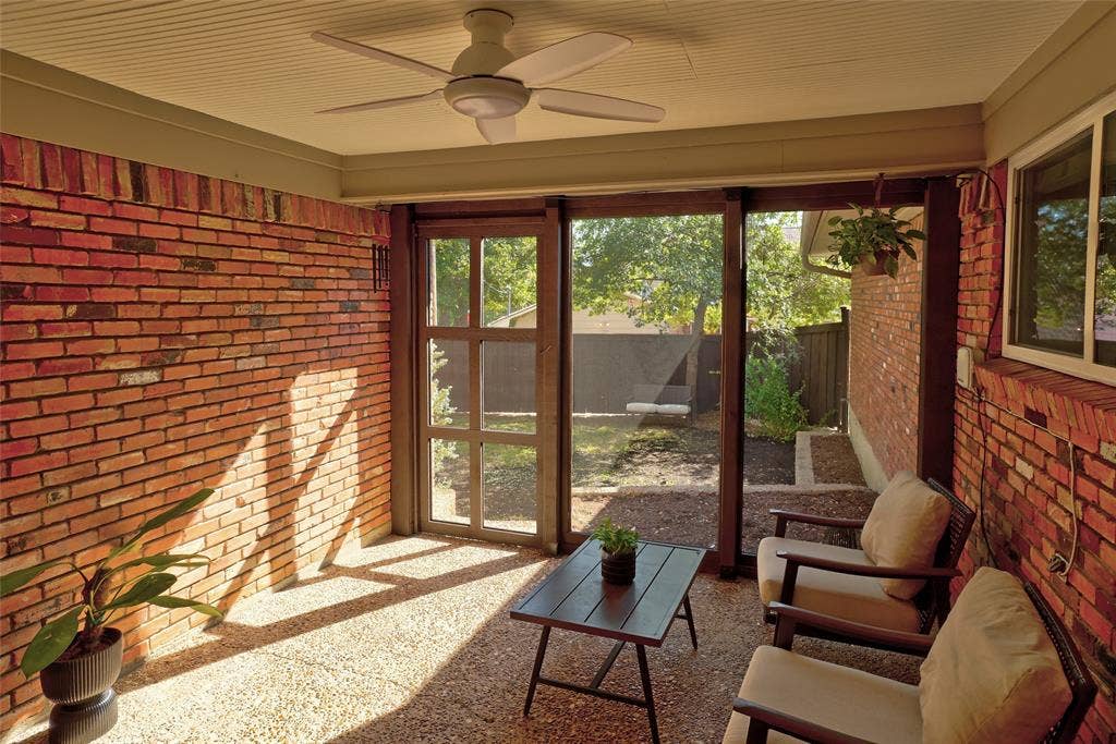 Covered patio featuring exposed brick walls, a beadboard ceiling, a ceiling fan, and screen enclosure