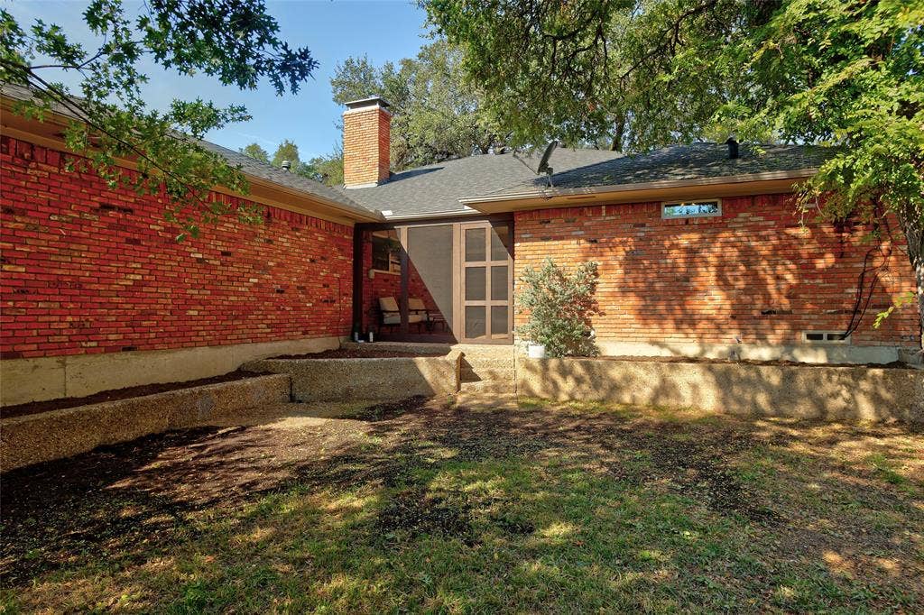 Red brick exterior with an elevated concrete retaining wall, chimney, and screened door entrance