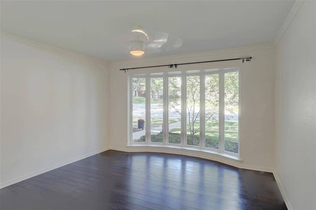 Large bay window with multiple panes, dark wood-finish flooring, and ceiling-mounted light fixture with integrated fan