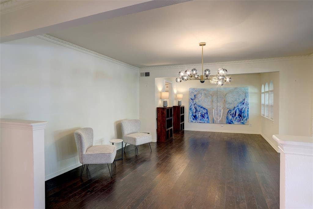 Dark wood-finish flooring, crown molding, and a multi-globe contemporary chandelier