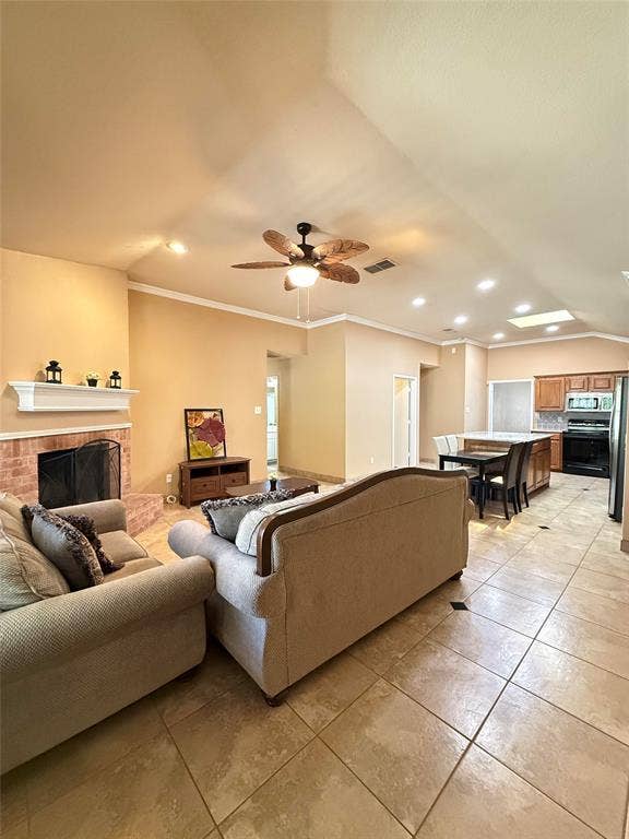 Vaulted ceilings with recessed lighting, brick fireplace with a decorative mantel, ceiling fan, and ceramic tile flooring