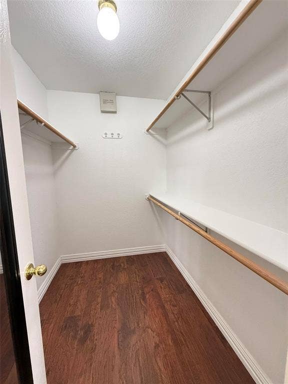 Storage space featuring wood-finish flooring, multi-level shelving, and built-in closet rods