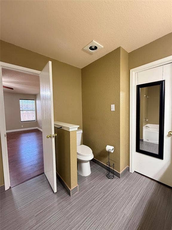 Bathroom area featuring neutral wall paint, wood-finish flooring, and an elevated half-wall partition